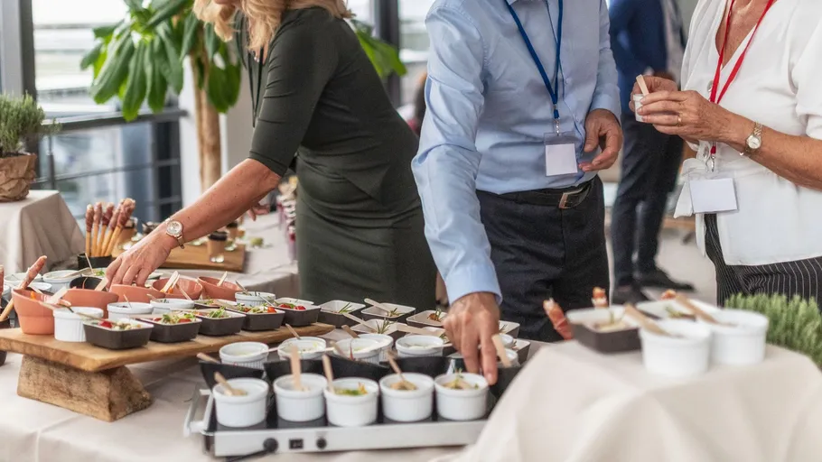 People selecting food from a buffet at a gathering.