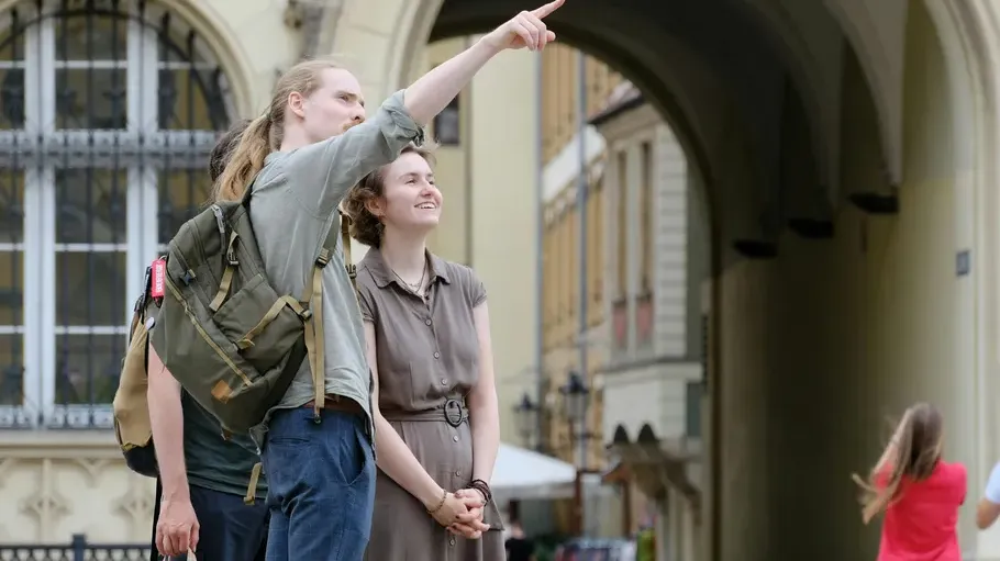 Two people pointing under archway outdoors.