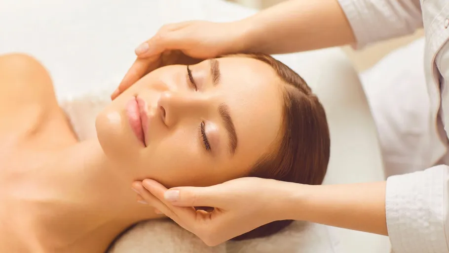 Woman receiving facial massage on bed.