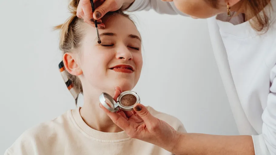 Woman having eyeshadow applied by another person.
