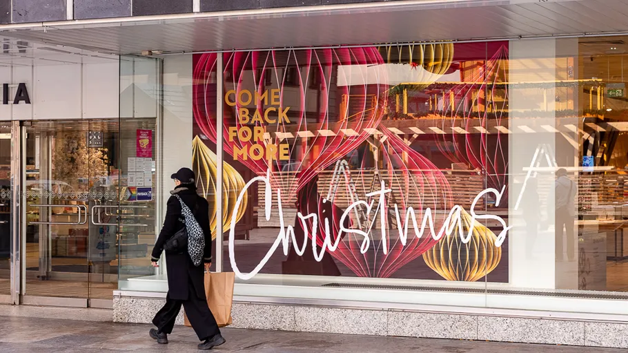 Woman walks past Christmas-themed store display.