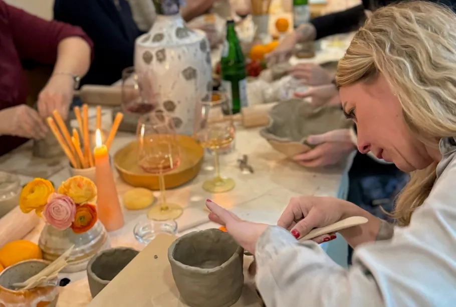 People creating pottery at a table workshop.
