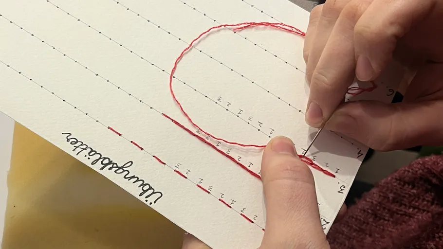 Hände nähen Zahlen auf Papier mit Nadel.