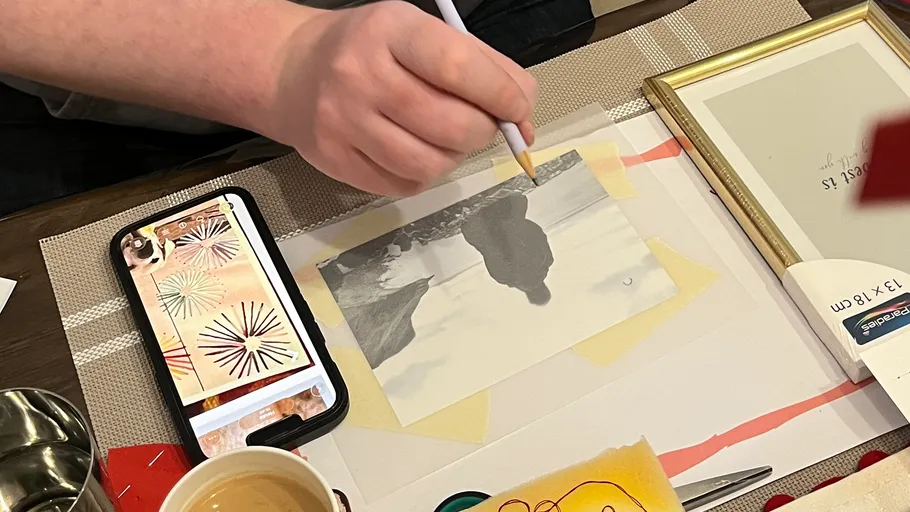 Person zeichnet auf Papier am Schreibtisch.