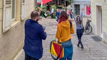 Leute gehen auf Straße, halten Flaschen, feiern.