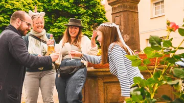 Gruppe von Freunden lacht und stößt im Freien an.