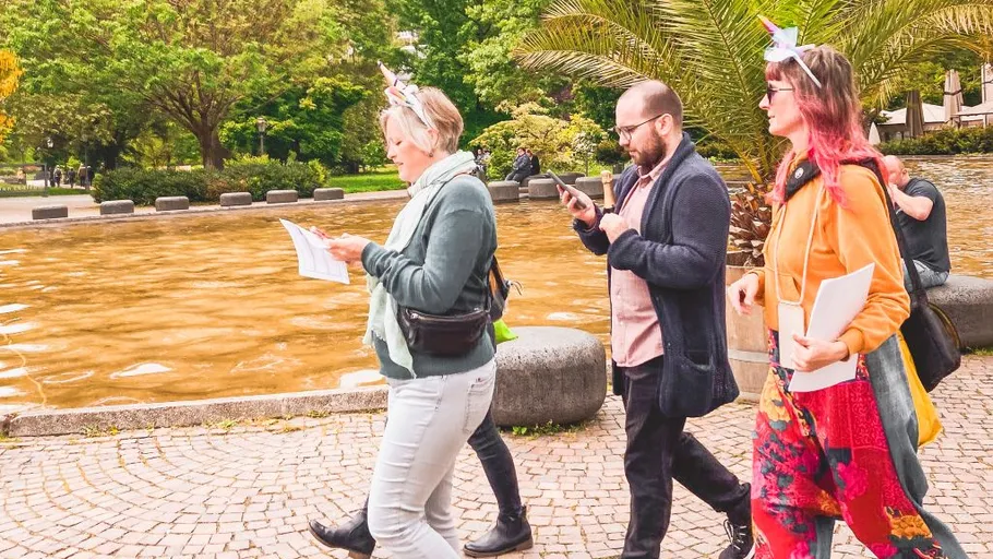 Three people walking in a park near a pond.