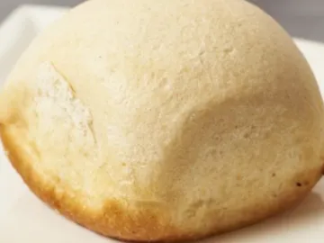 Round roll rests on a white plate, slightly browned.