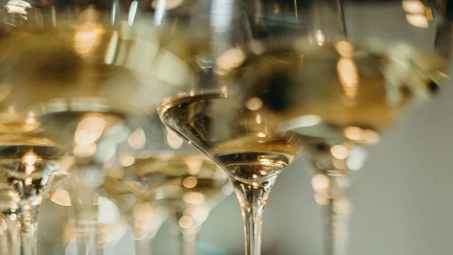 Wine glasses filled with white wine, blurred background.