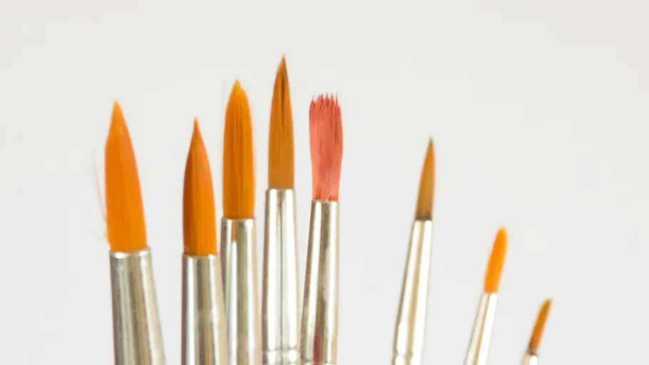 Various paintbrushes with orange bristles displayed upright.
