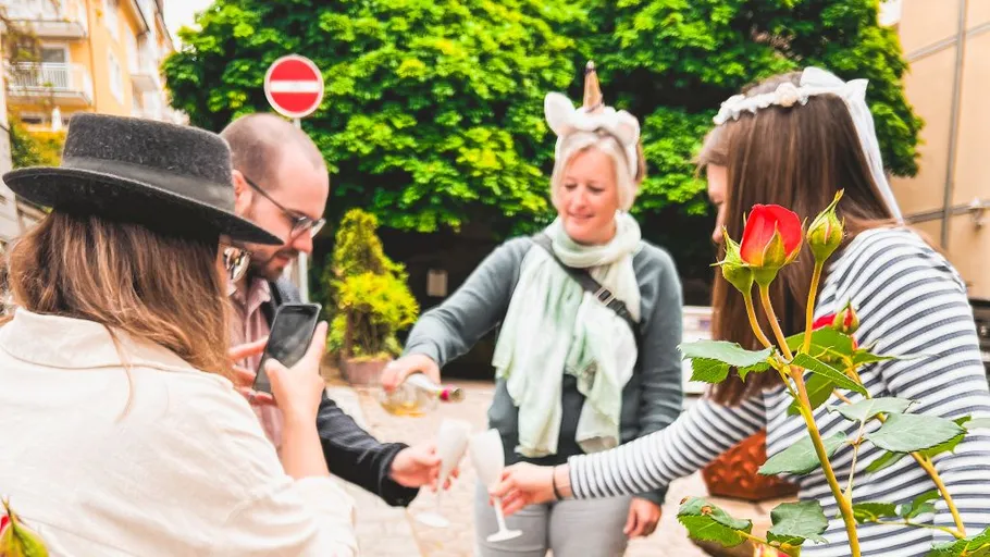 Group sharing drinks outdoors by rose bush.