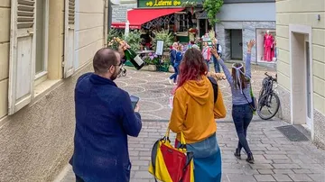 Personen mit erhobenen Händen in schmaler Straße.
