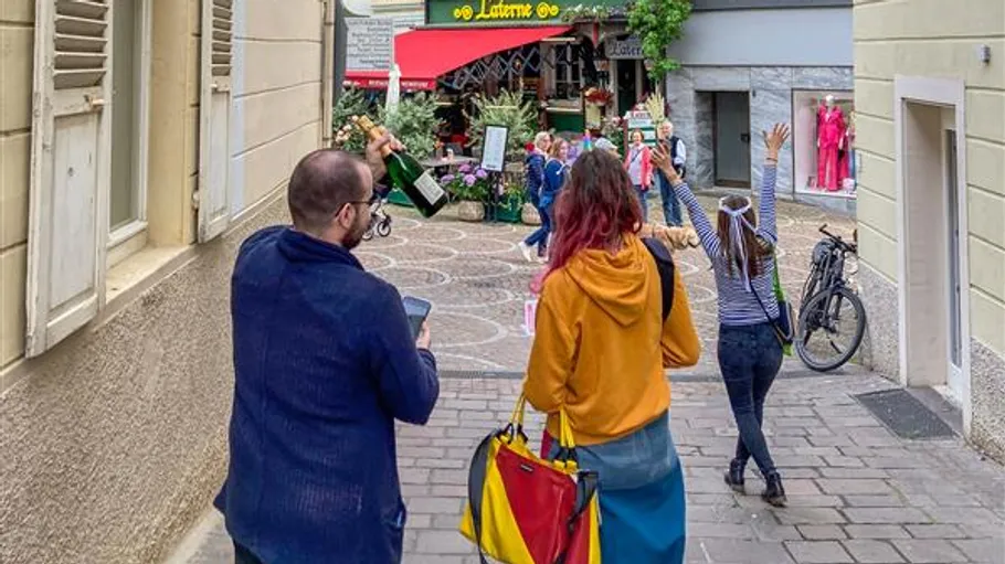 People with raised hands walking in narrow street.
