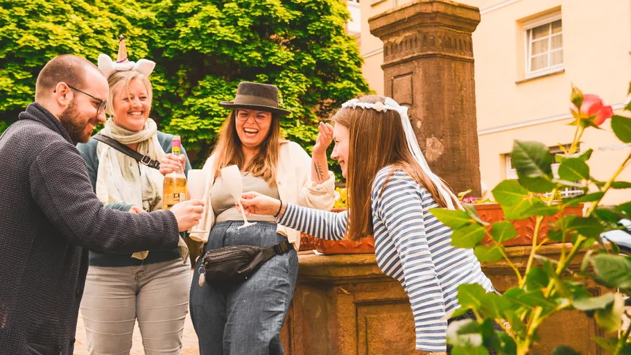 Four people laughing and toasting outdoors.