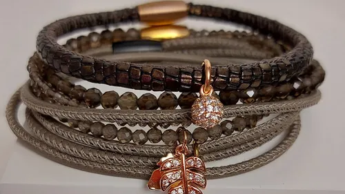 Stacked bracelets with charms on white surface.