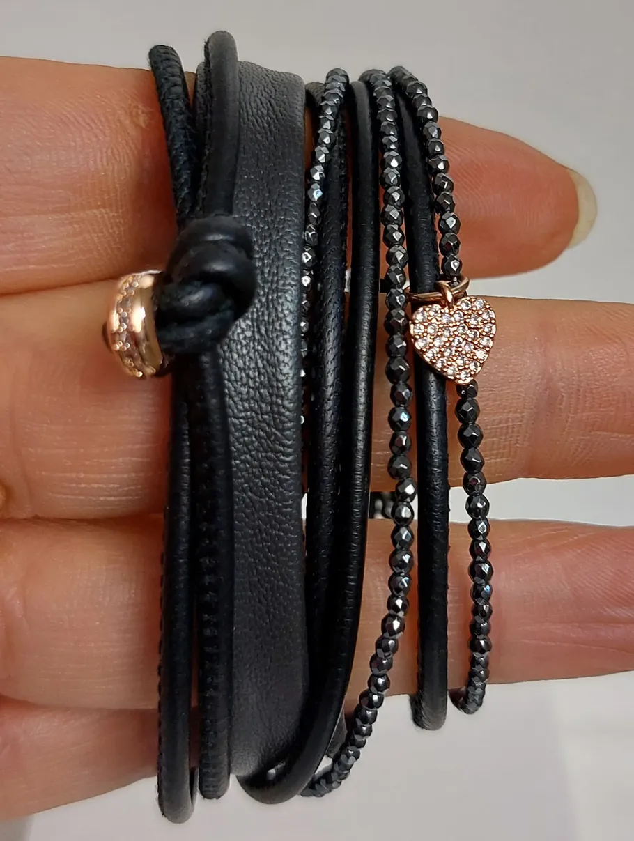 Schwarzes Armband mit Herzanhänger, in Hand gehalten.
