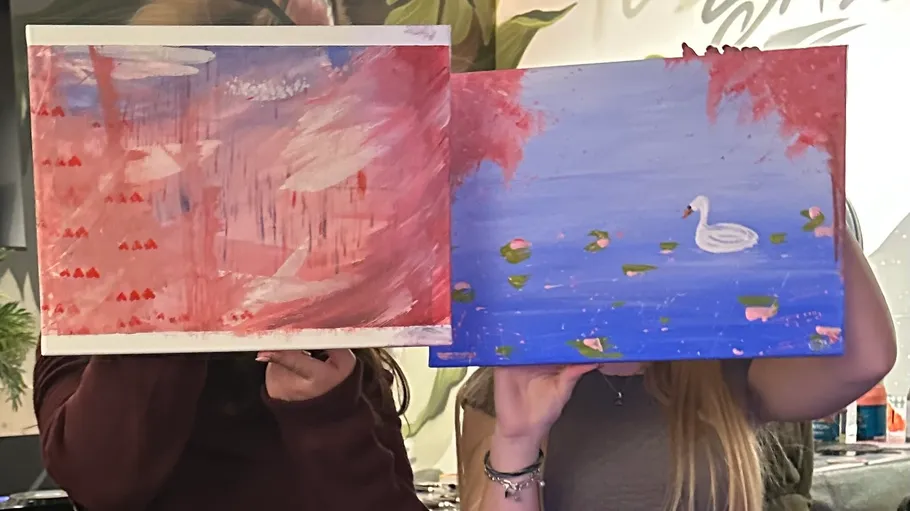 Two people holding colorful abstract paintings.