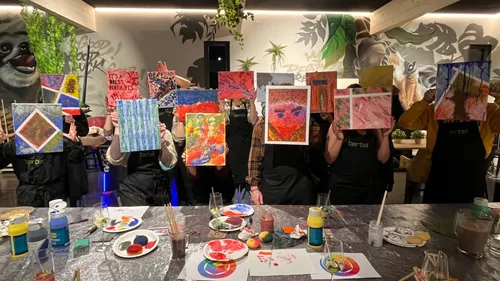 Group holding painted canvases in art studio.