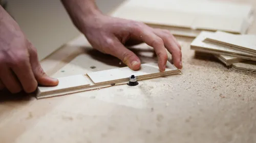 Hands assembling wooden pieces on workbench.