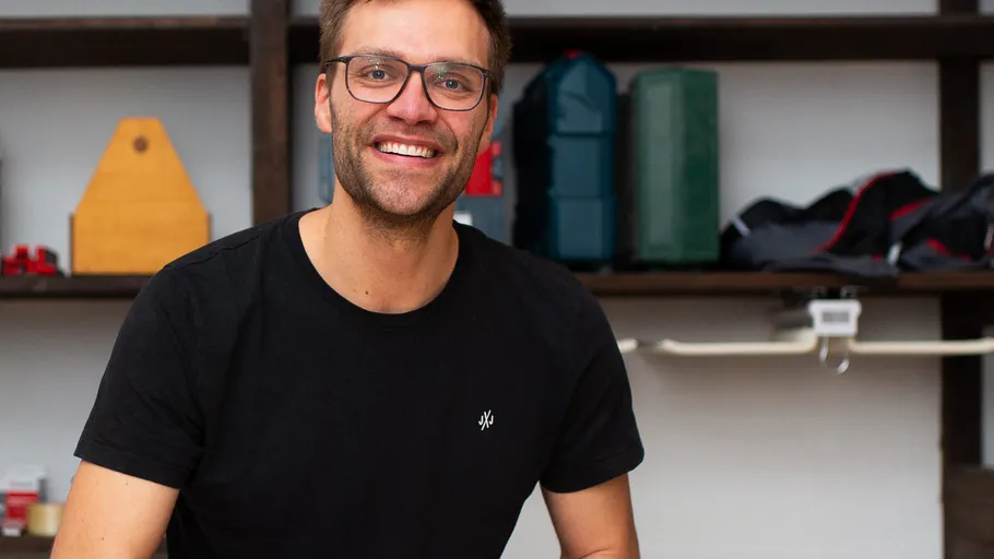 Smiling man wearing glasses, standing indoors.