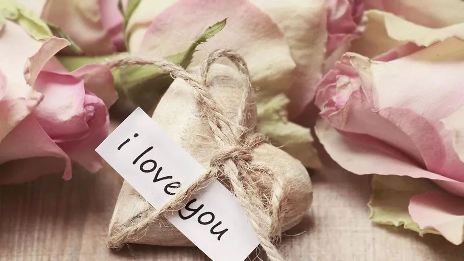 Wooden heart with roses and 'I love you' note.
