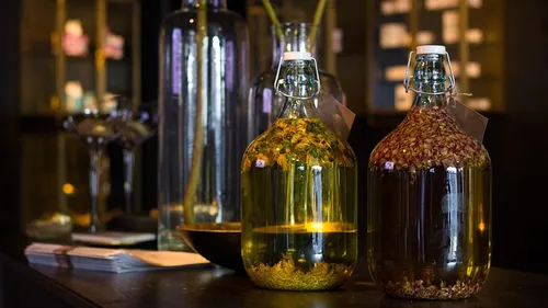 Two glass bottles with herbs, dark background.