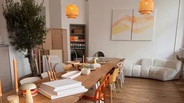 Gemütliches Studio mit langem Tisch und Kunstmaterialien.