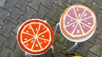 Zwei obstgemusterte Hocker auf gepflastertem Boden.