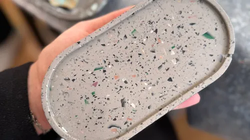 Hand holds speckled oval tray indoors.