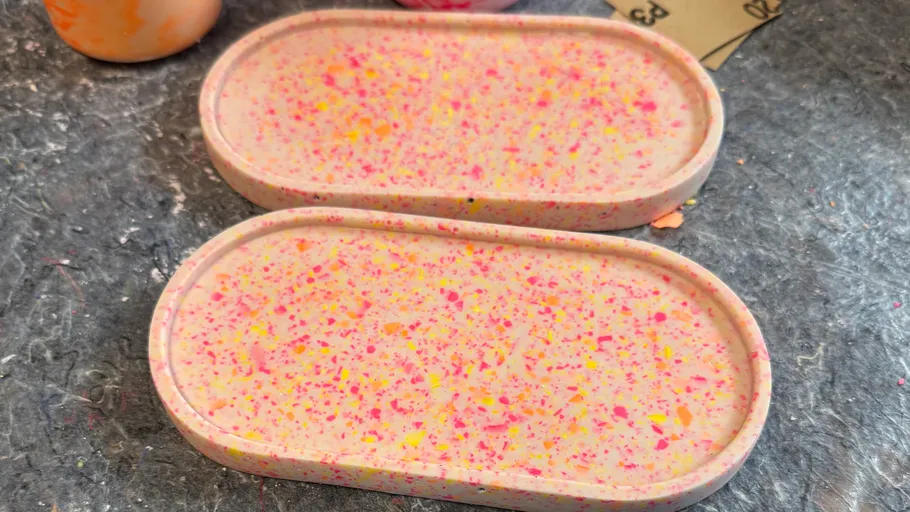 Two speckled trays on a textured surface.