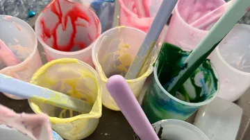 Bunte Farbbecher mit Rührstäben.