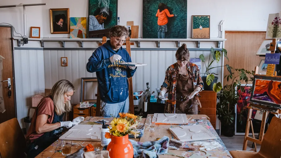 Drei Künstler arbeiten an Gemälden im Atelier.