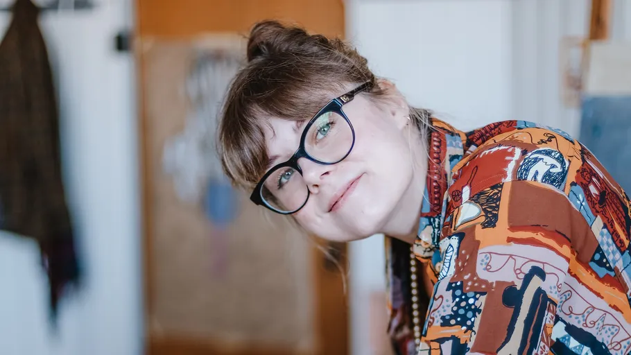 Person mit Brille lächelt, trägt buntes Hemd.