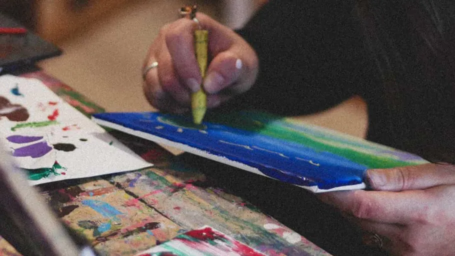 Person painting with crayons on colorful paper.