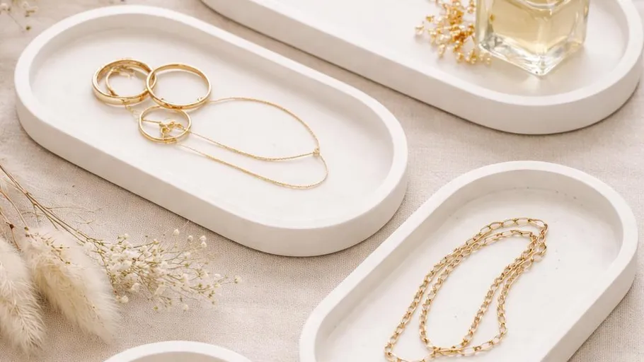 Gold jewelry on white ceramic trays, elegant setting.