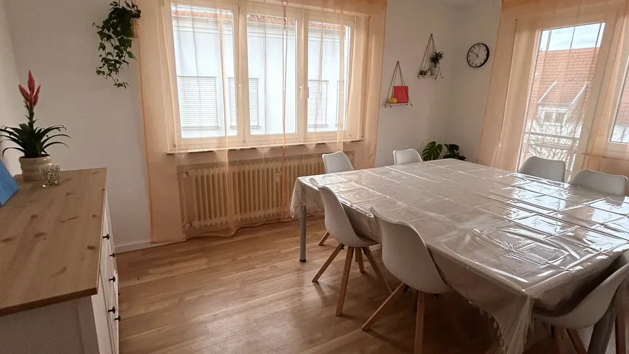 Esszimmer mit Tisch, Stühlen und Pflanzen.