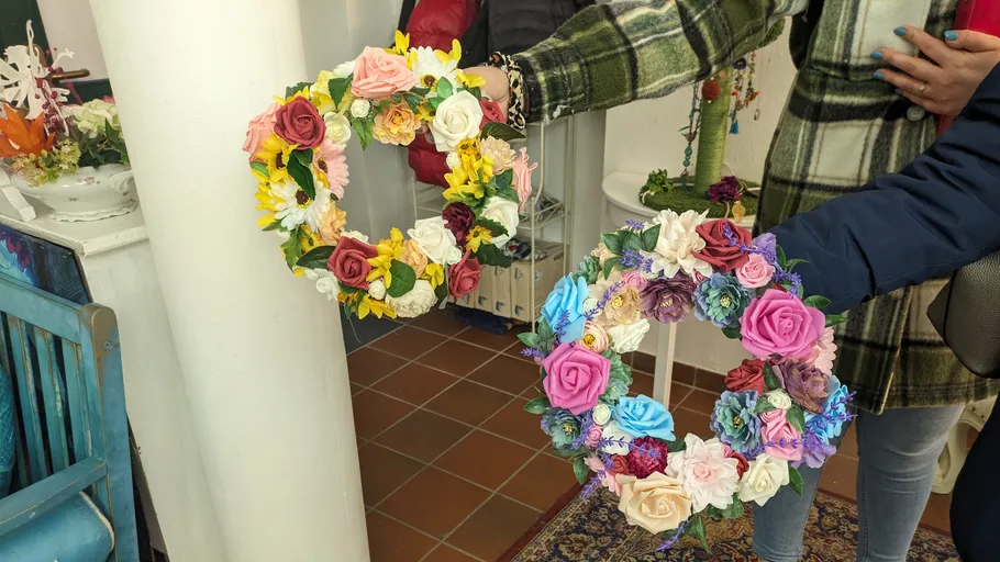 Personen halten bunte Blumenkränze drinnen.
