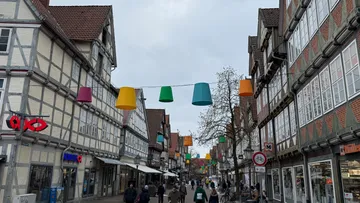Bunte Laternen hängen über Straße mit Geschäften.