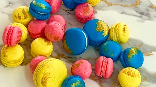 Bunte Macarons mit Goldakzenten auf Marmor.