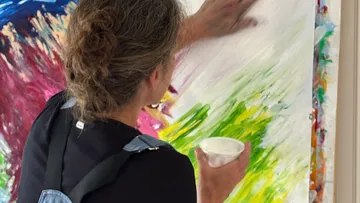 Artist painting on large colorful canvas.