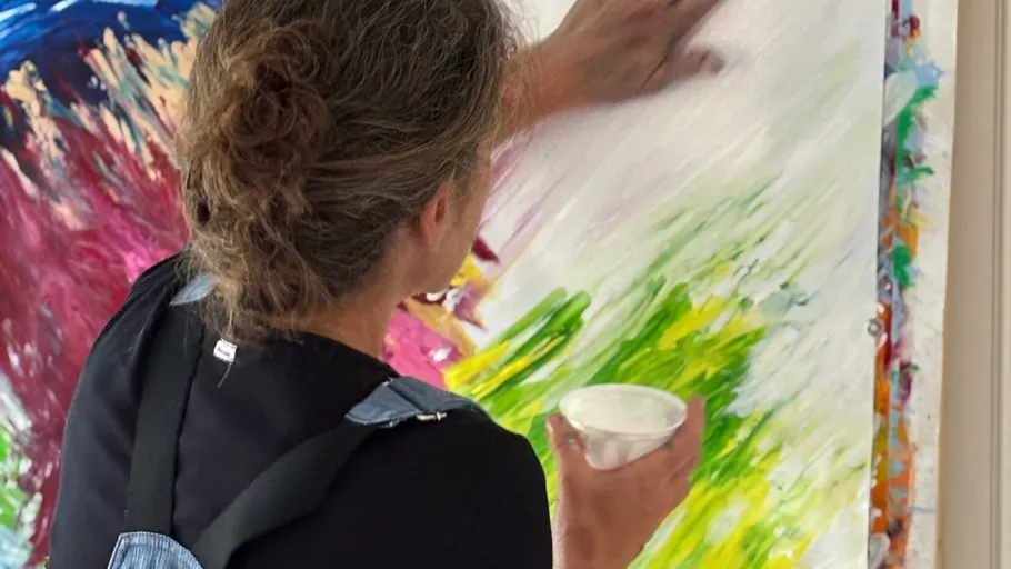 Artist painting on large colorful canvas.