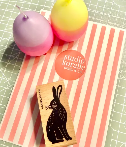 Colorful candles and rabbit stamp on striped paper.