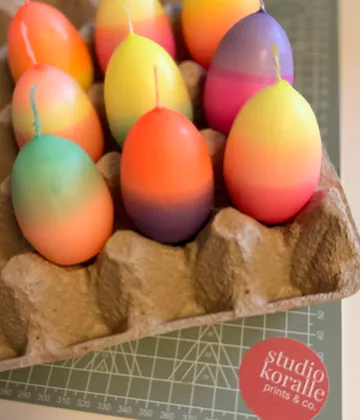 Bunte, eiförmige Kerzen in einem Tablett.