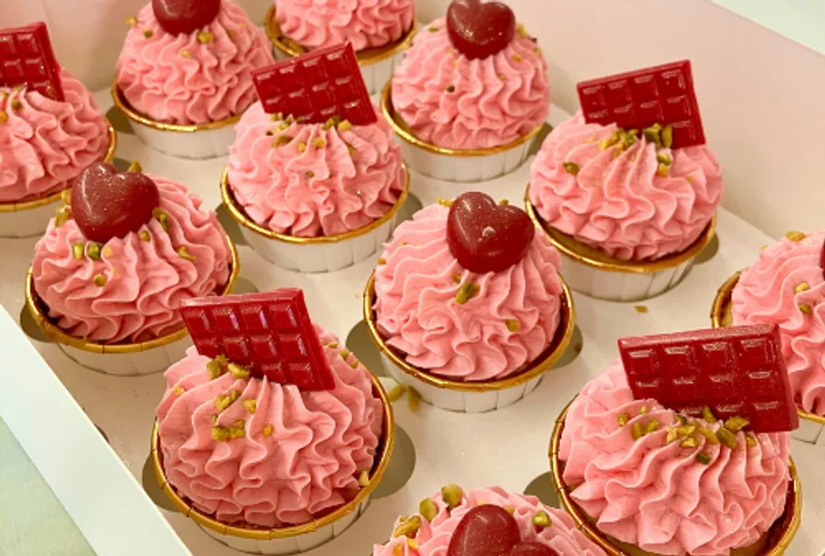Pink cupcakes with decorations in box.