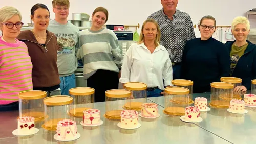 Group of people stands behind decorated cakes.