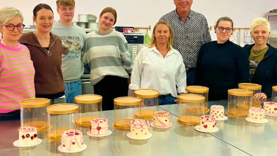 Gruppe von Personen steht hinter dekorierten Kuchen.