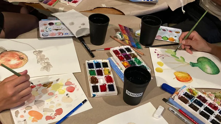 Hands painting watercolors at a table.