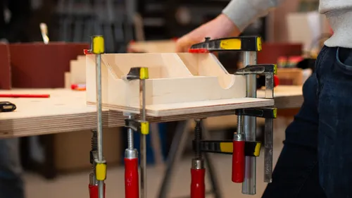 Person verwendet Klemmen an Holzprojekt in Werkstatt.
