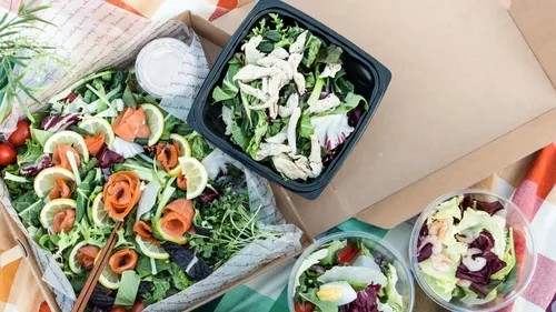 Salate und Grünzeug mit verschiedenen Belägen in Behältern.