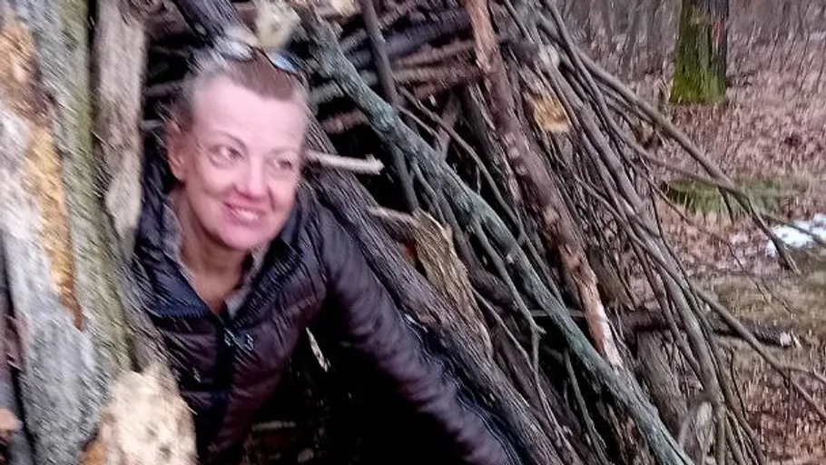 Woman in a forest hut made of branches.